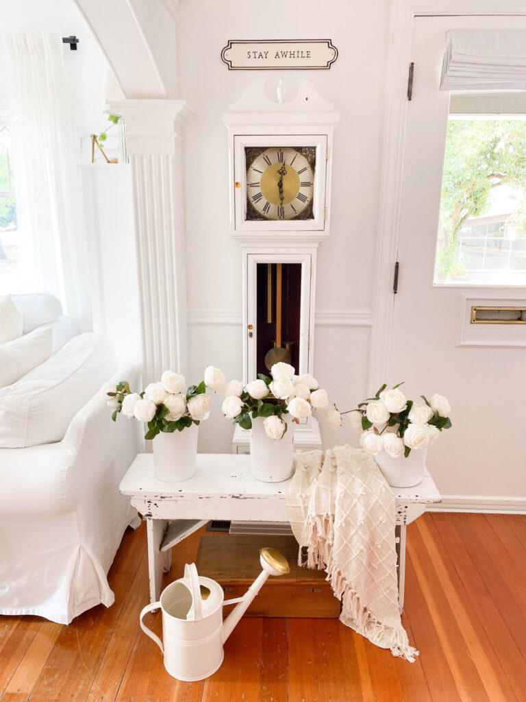 Small cottage entryway with antique farm bench, grandfather clock and spring florals for small entryway styling ideas