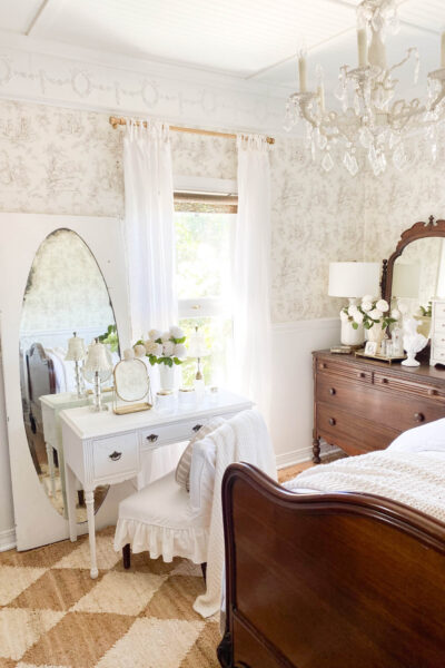 Image of a nuetral bedroom with antique furniture and a small bedroom vanity