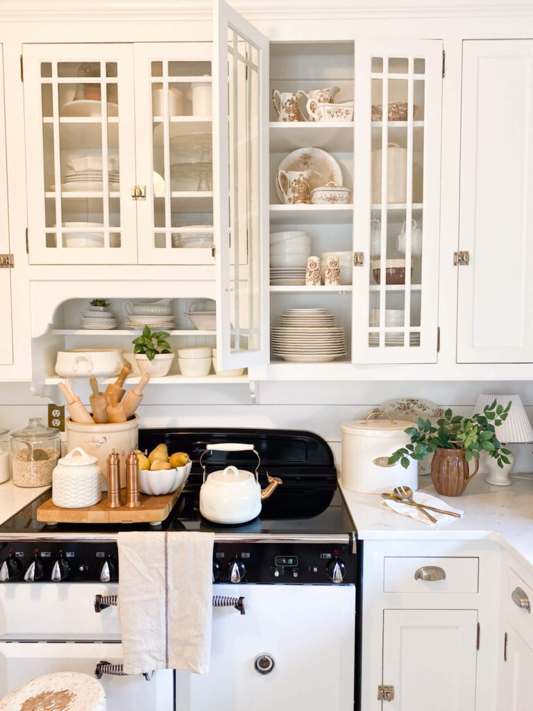 Image of a white cottage kitchen with glass doors show casing antique ironstone dishes