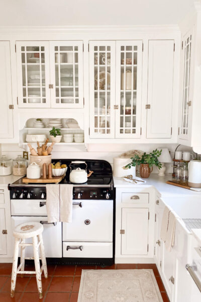 Image of a cottage style kitchen with white cabinets, AGA vintage inspired stove and farm sink