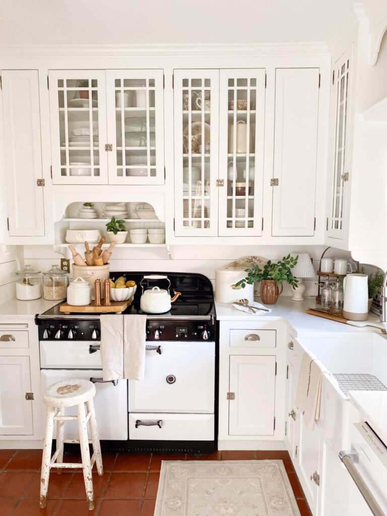Image of a cottage style kitchen with white cabinets, AGA vintage inspired stove and farm sink