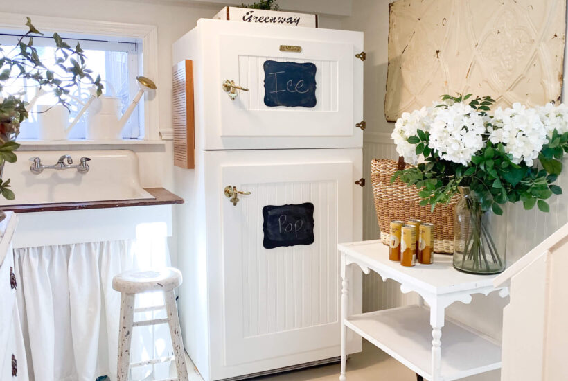 Image of a vintage style refrigerator with an antique tea cart with white spring flowers and drinks on it