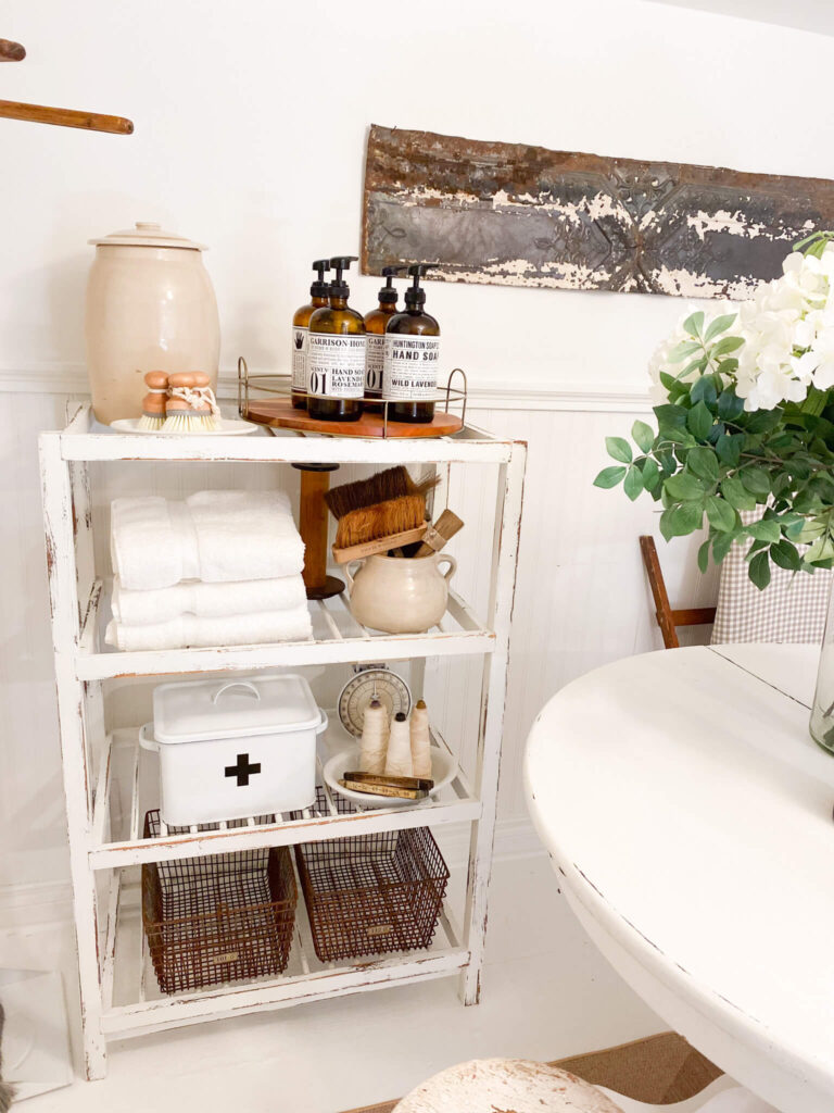 An old bakers rack with decorative cleaning supplies and vintage items for a basement laundry room refresh