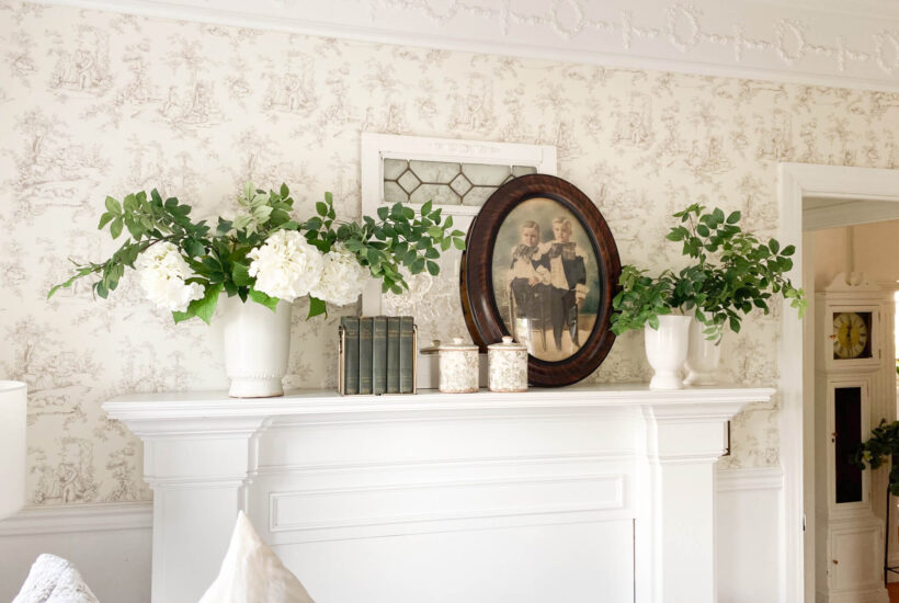 Image of a white mantel, vintage portrait with oval frame with two vases and white flowers