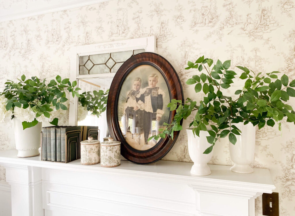 Mantel styling tips - antique mirror, antique protrait in the middle of 3 vases with green stems and spring florals on either side