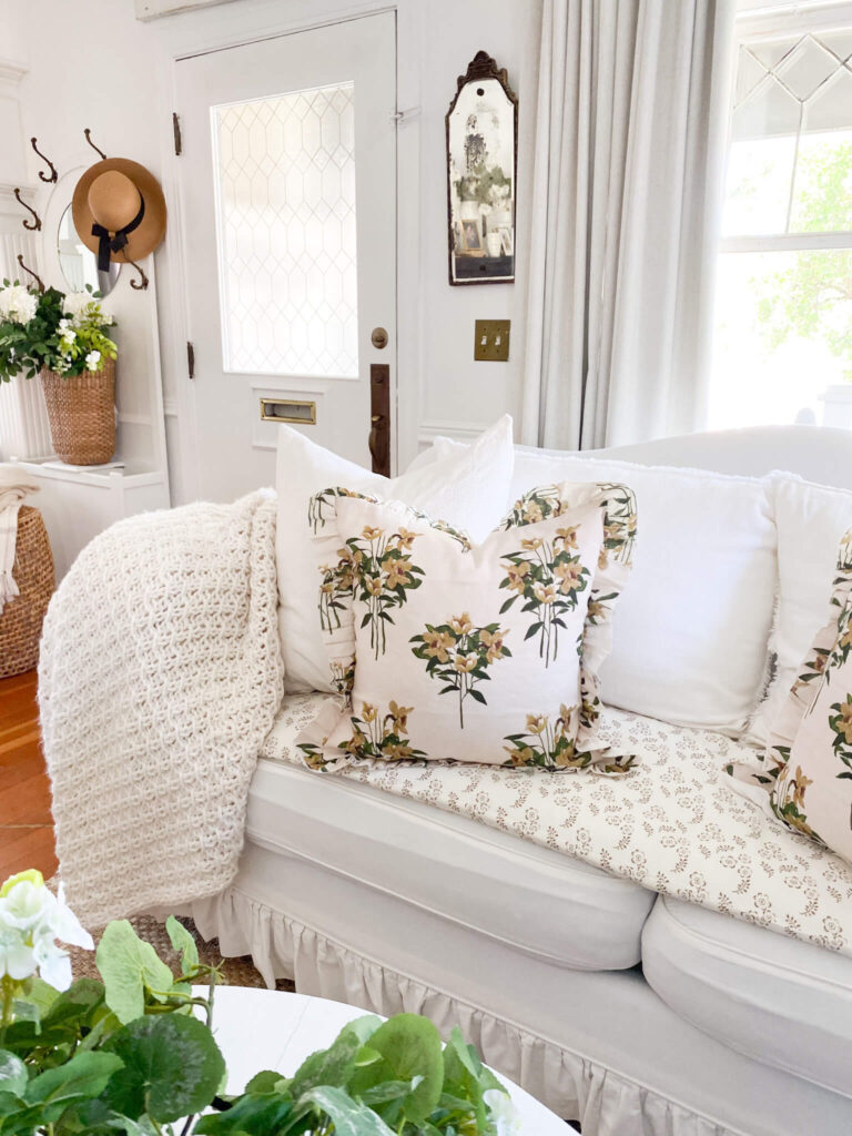 Cottage slip covered couch with floral ruffled pillow and petite patterned sofa topper for a small cottage living room