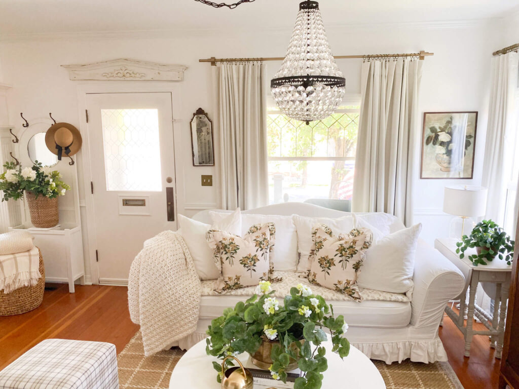 White slipcovered couch with ruffled floral pillows and a sofa topper with petite flowers