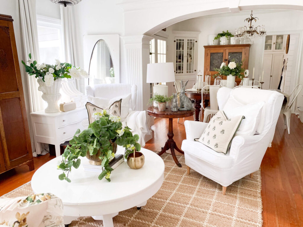 Two white slipcovered wing back chairs and a large urn of white hydrangeas