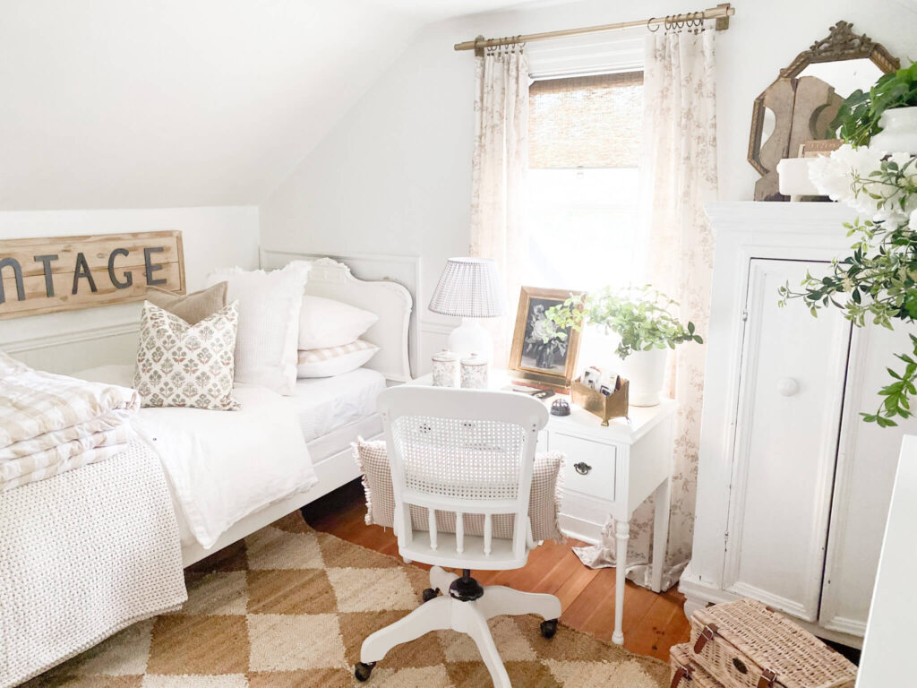 White layered antique bed with vintage writing desk and floral curtains for a blog titled cozy room ideas