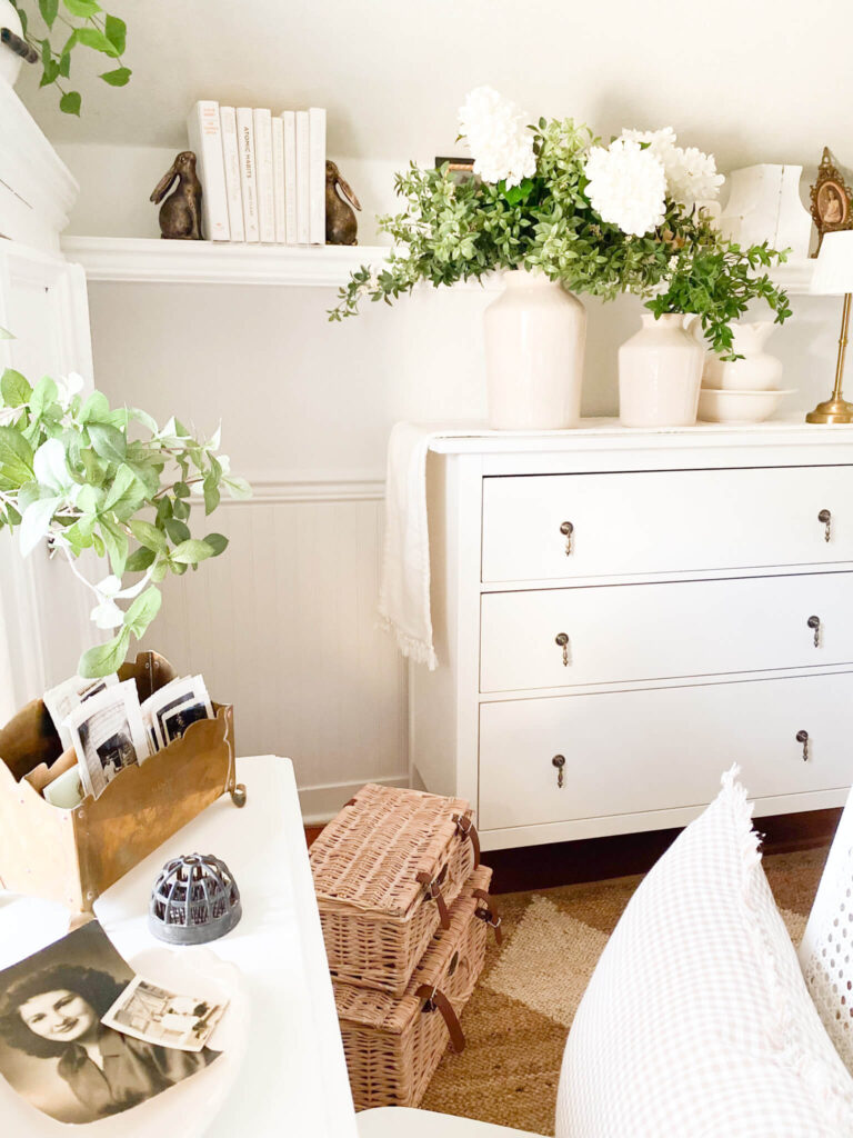 Small cottage bedroom with white dresser, books and vintage photos