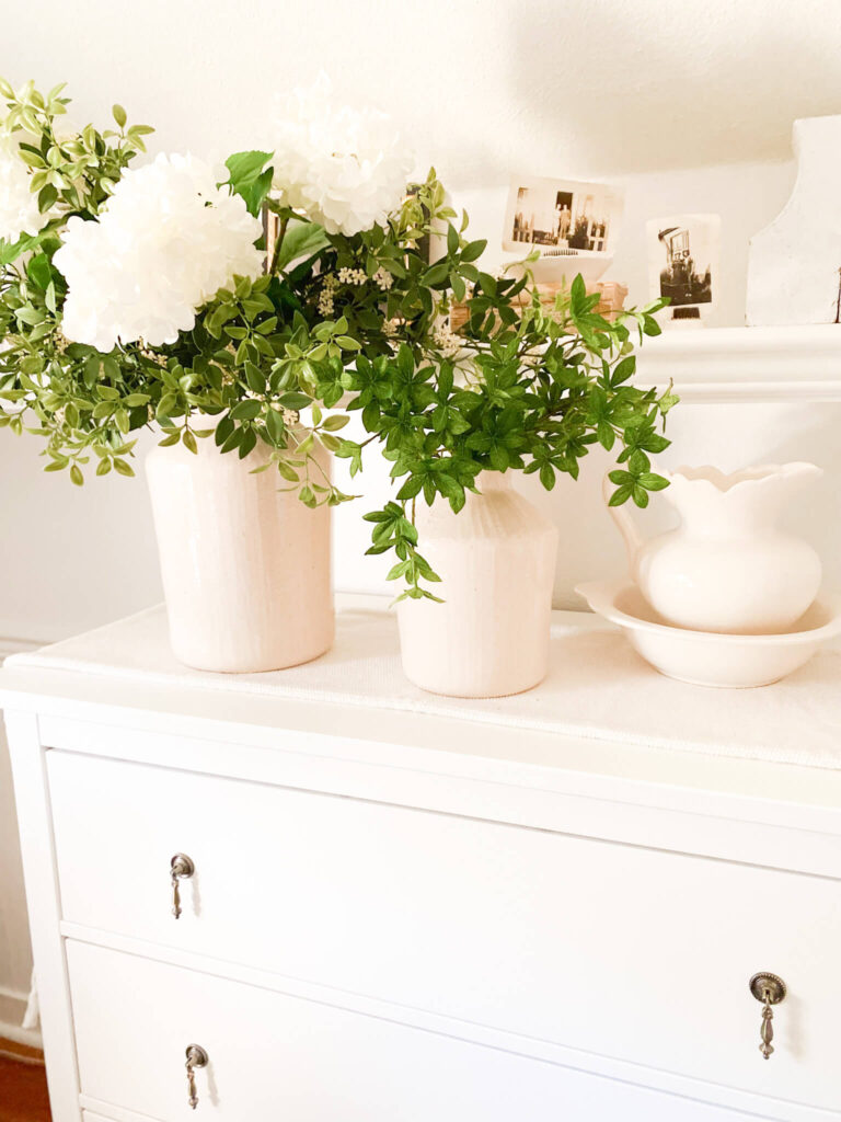 Spring florals and greenery with vintate pitcher on a white cottage dresser