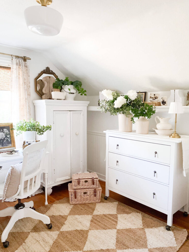 White cottage bedroom featuring vintage white antique furniture, a jute rug, white spring florals and vintage decor
