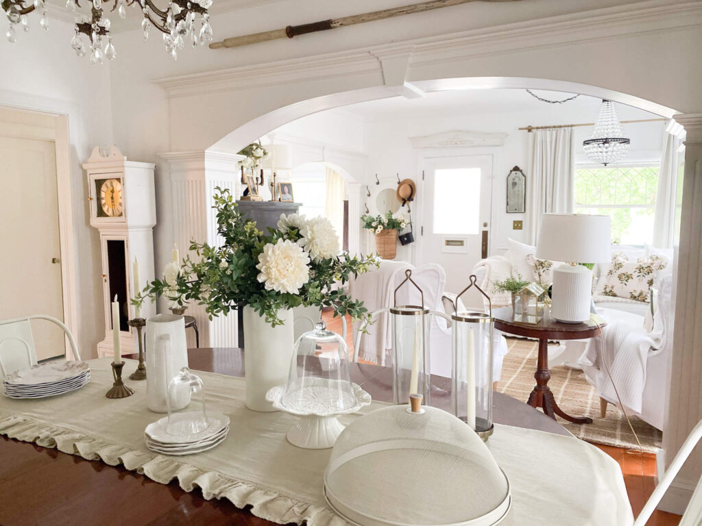 Antique table set for lunch with white dishes and a large white floral centerpiece