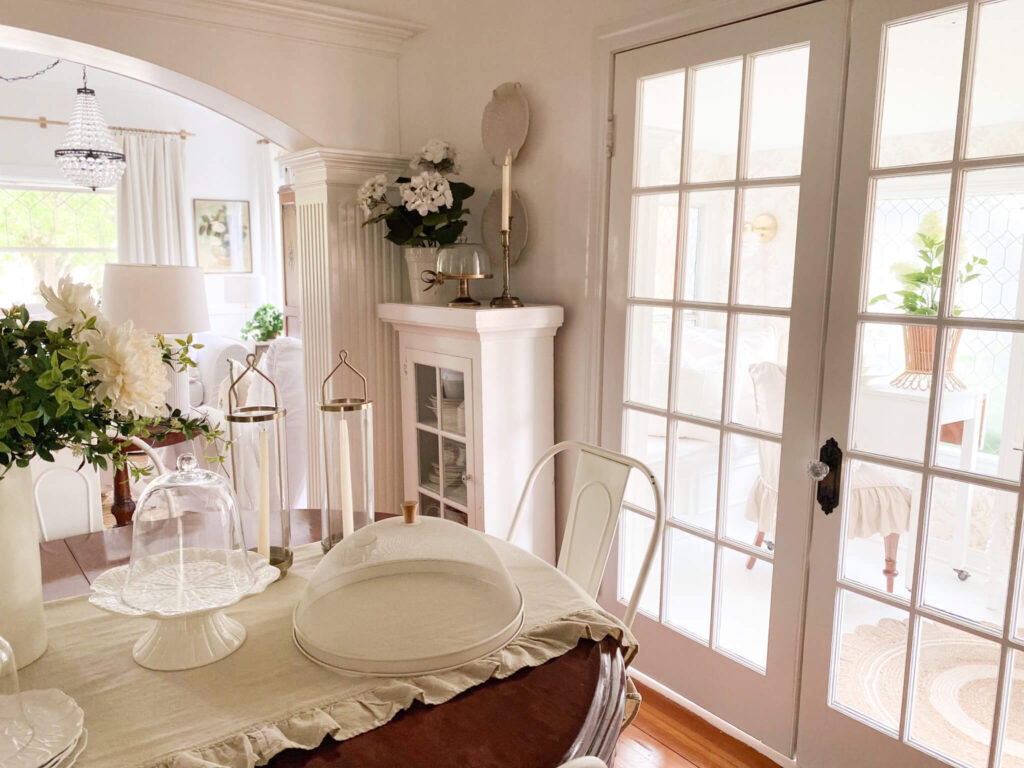 Cottage dining room with lots of white dishes old and new with vintage glass french doors