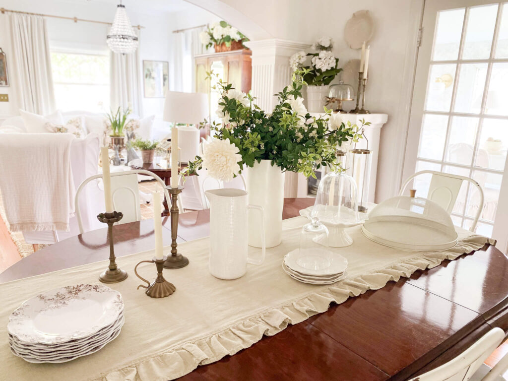 Spring dining room with spring florals, cabbage cake plate, brown and white transferware dishes and a ruffled table runner