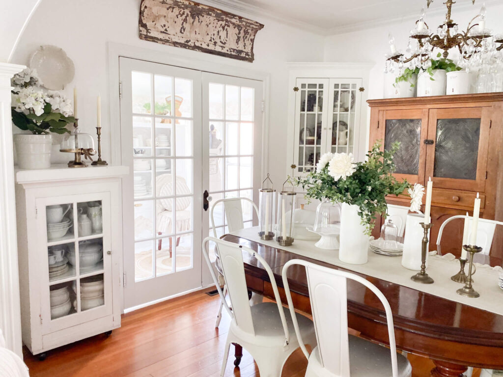 Cottage dining room with oval antique table and a vintage pie cupboard
