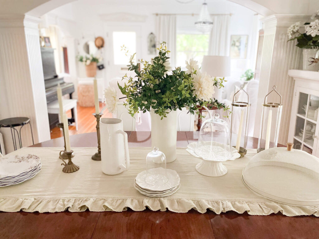 A dining tablescape with flowers, white dishes, brown and white transferware plates and brass candelabras