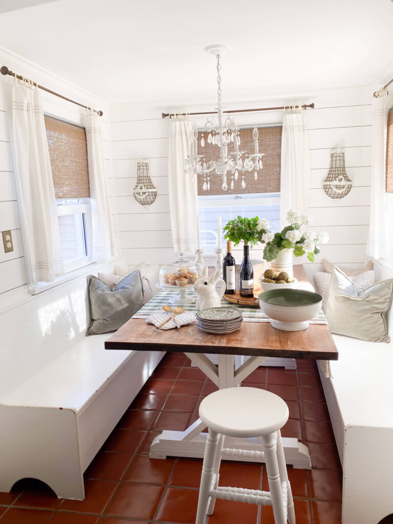 Farmhouse breakfast table, shiplap walls, green pillows and a gingham tablelcloth