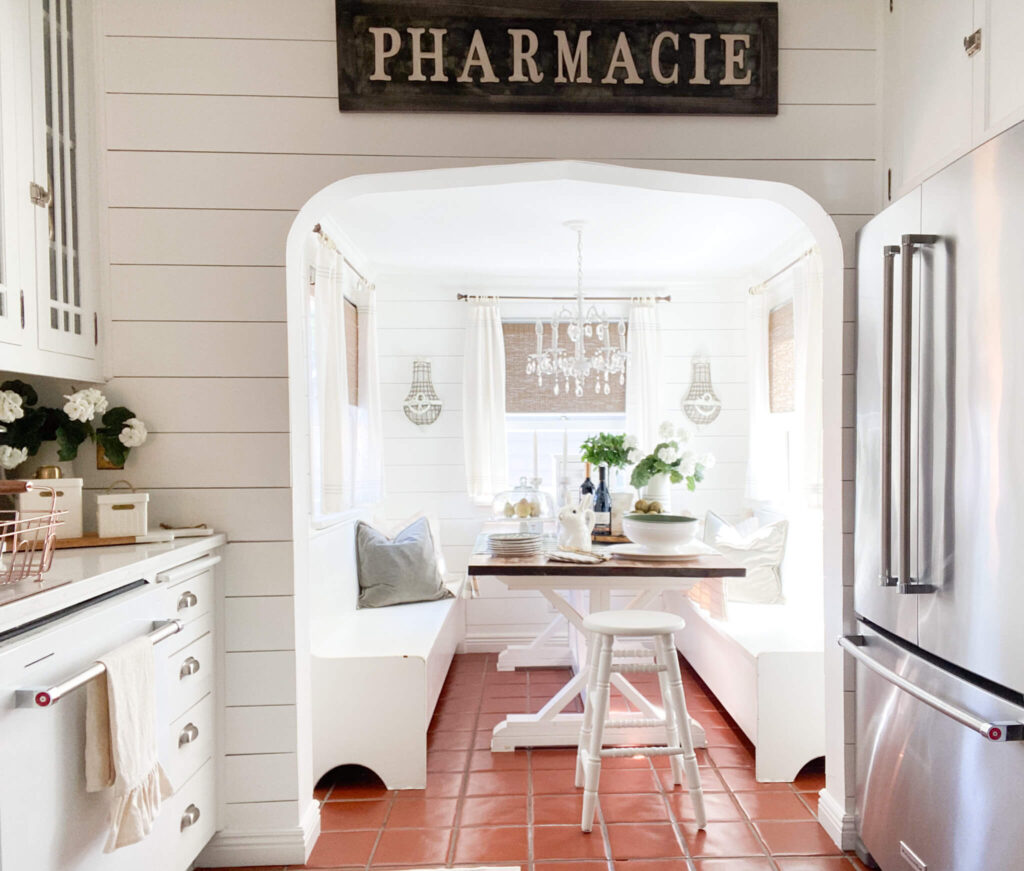 Vintage kitchen nook with a farm table and white bench seats and a large Pharmacie sign