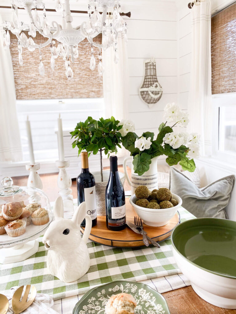 Kitchen nook table with white geraniums, green floral vintage style plates and a chandelier