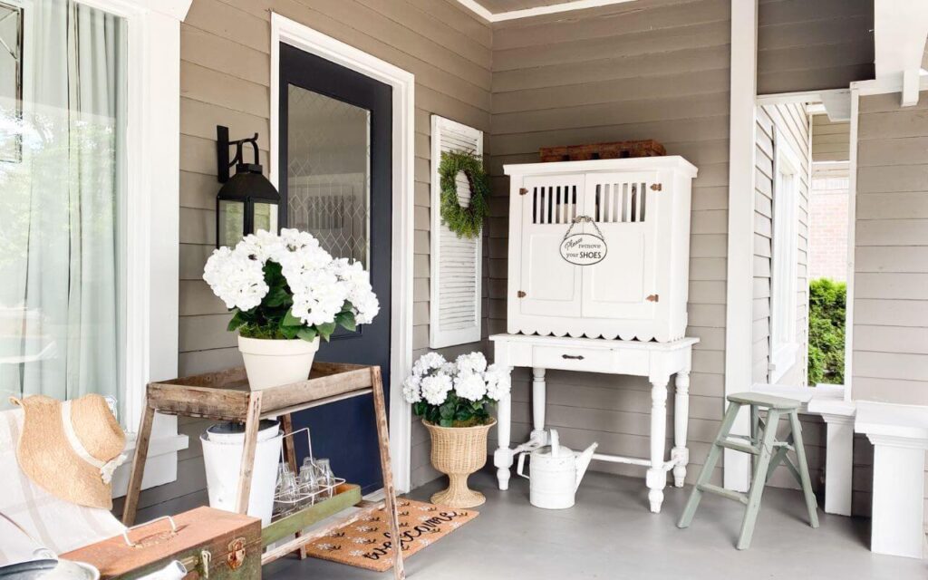 White cottage porch decorated for summer with white faux florals