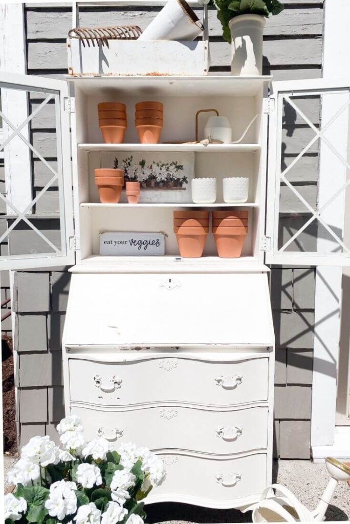 Potting bench from old desk with terra cotta pots and gardening tools for a summer patio refresh