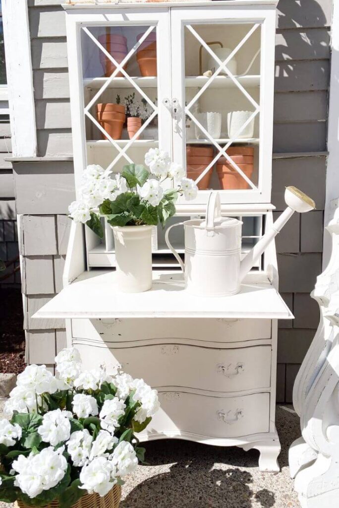 Vintage desk upcycled into a potting bench with terra cota pots and faux florals