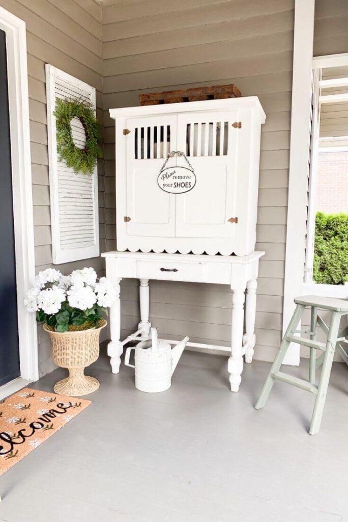 Vintage white cottage cupboard with faux white potted florals and vintage watering can.