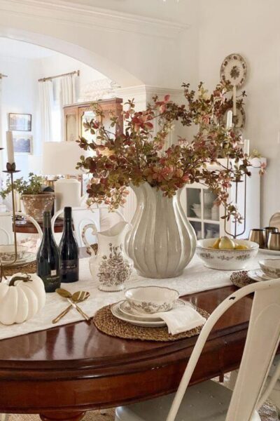 Formal dining room styled for fall with fall stems and brown transferware everyday dishes