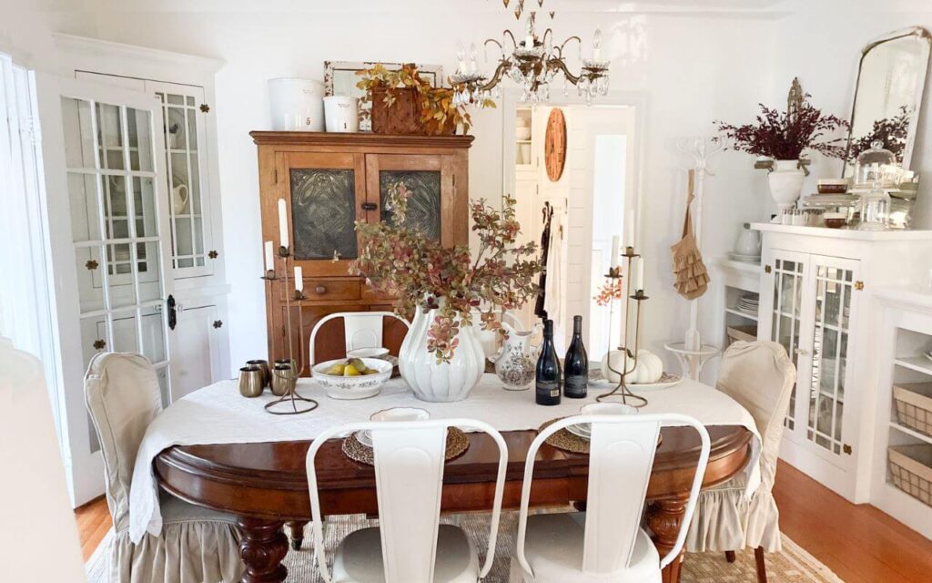 Fall decor in a cozy cottage dining room with slipcovered chairs and vintage dishes