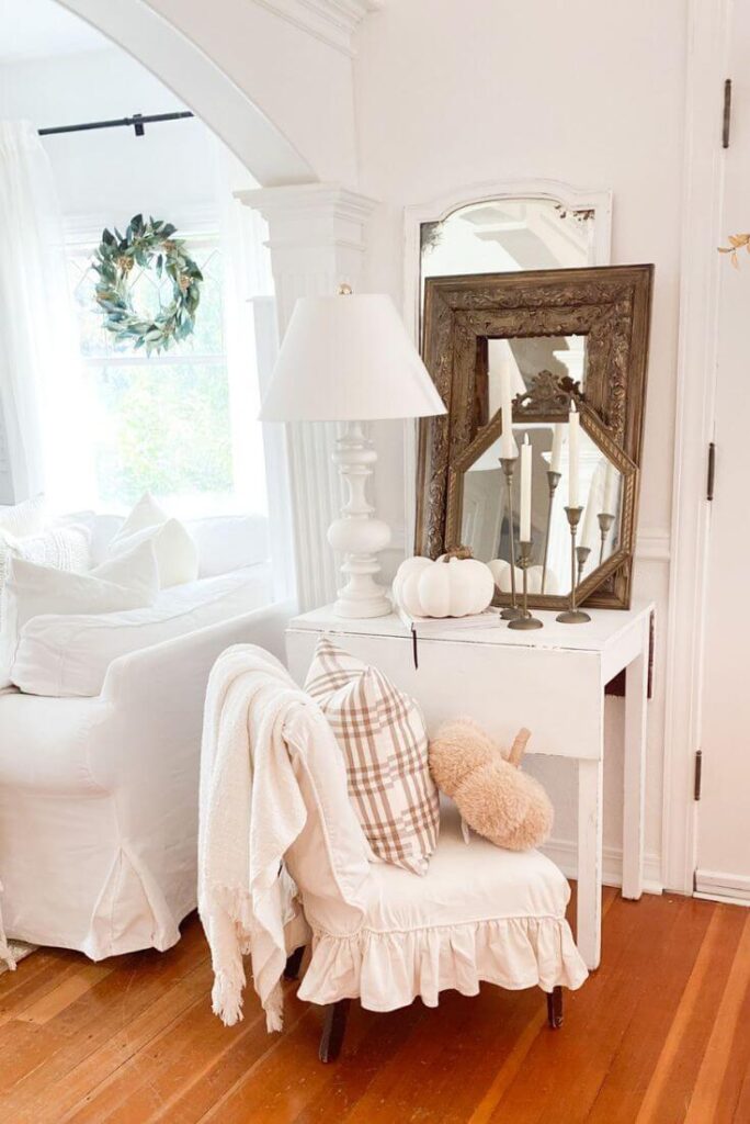Small cottage entryway styled for fall with gold antique mirrors and plaid pillows.