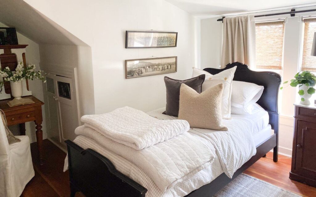 Small vintage bedroom styled with vintage wood furniture and an antique bed painted charcoal black