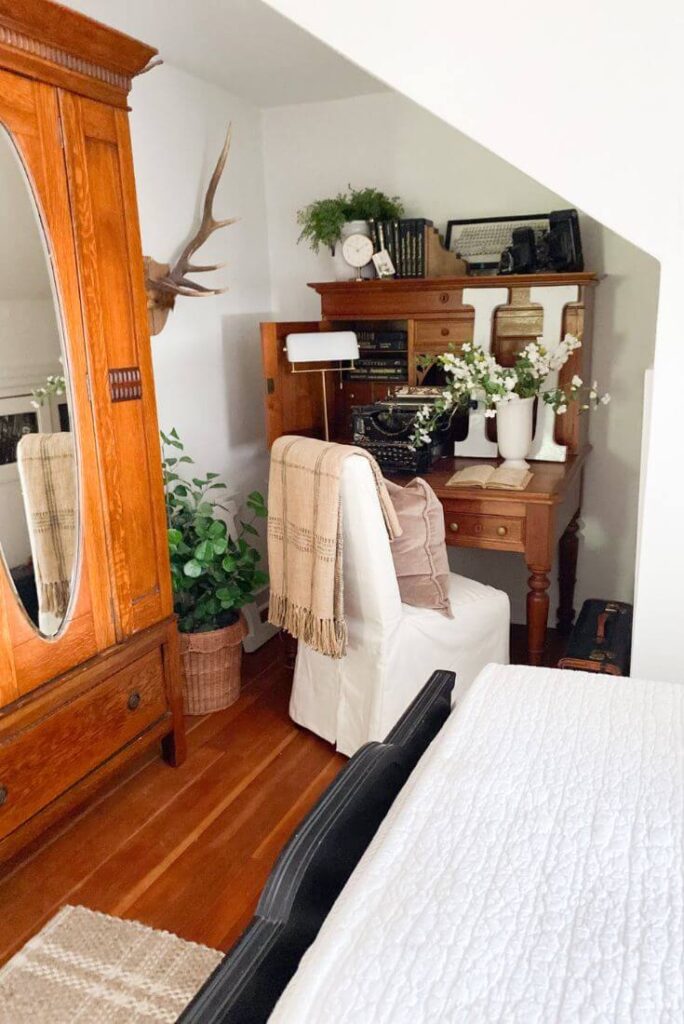 Small cottage bedroom with layered neutrals and antique furniture