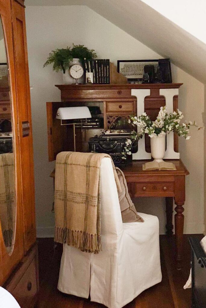 Cozy corner of small cottage bedroom with antique desk and chair