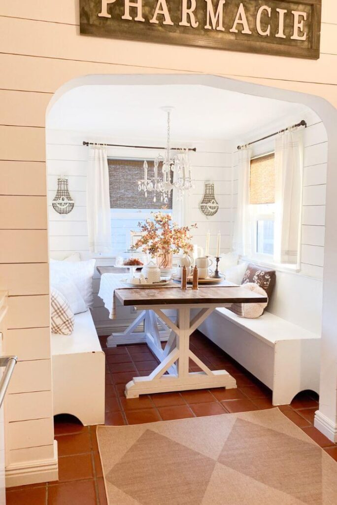 Cottage-style kitchen nook with white cabinetry and cozy fall touches