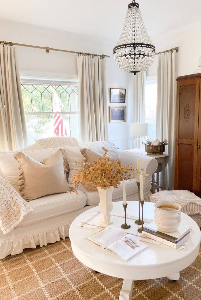 Cottage-inspired living room styled for fall with cozy throws, linen pillows, and rustic charm.