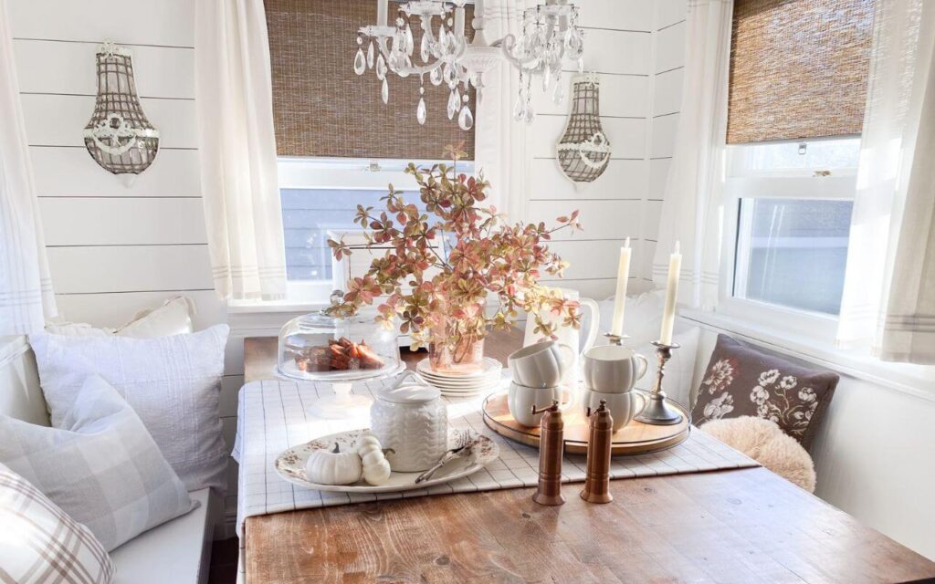Close-up a vintage cake plate with dessert and pumpkins on a cottage kitchen table styled for fall