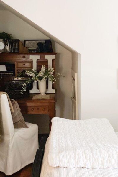 Vintage desk styled in small cottage bedroom with books and photos