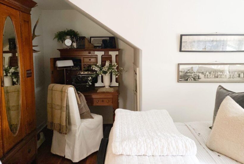 Vintage desk styled in small cottage bedroom with books and photos