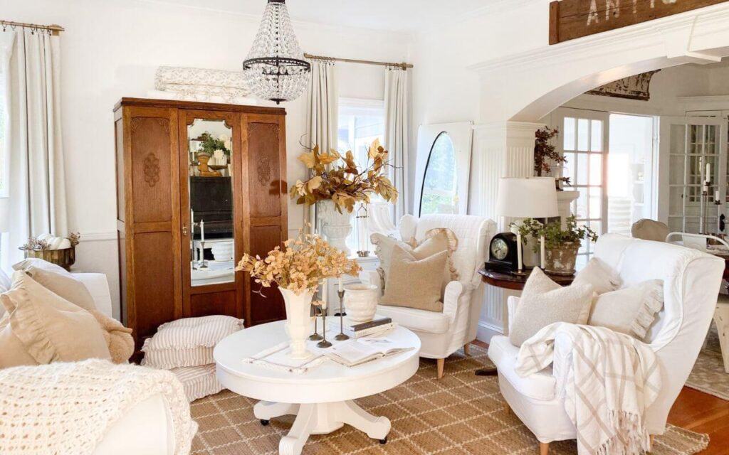 Neutral fall living room with cozy throws, quilted sofa, and warm fall stems in vases.