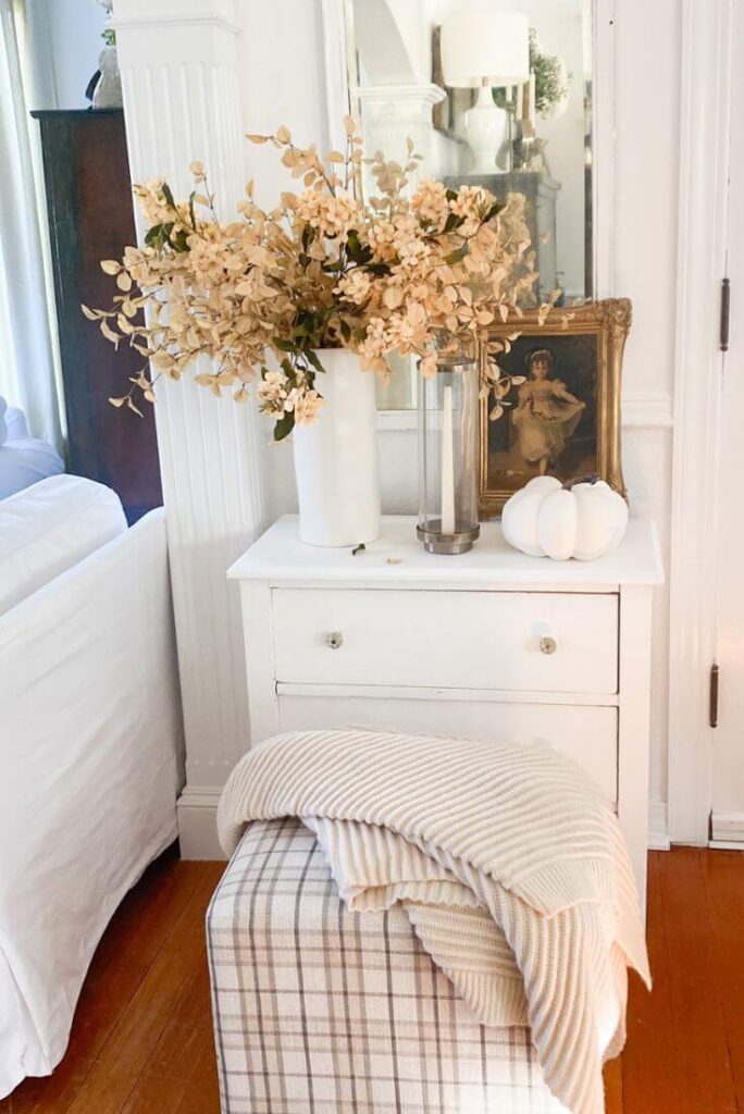 Cozy fall entryway decor with pumpkins, artwork, and layered textures.