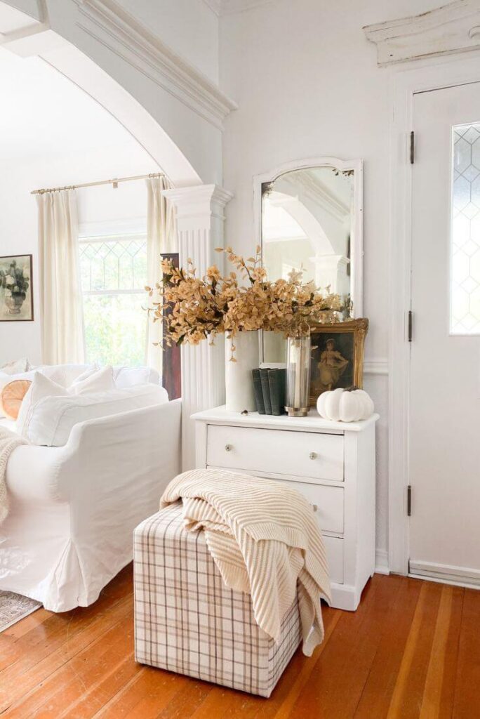 Entryway styled with vintage dresser, antique mirror, and cozy autumn accents.
