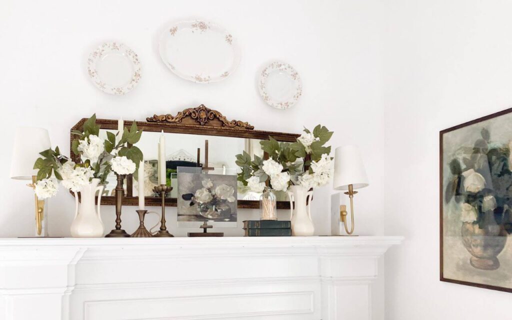 Detail shot of brass candelabra beside floral painting and old books