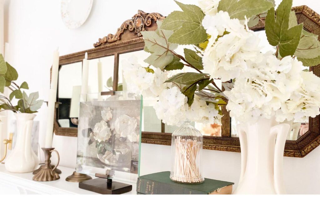 Close up view showing mantel styling with antique mirror and cozy cottage details