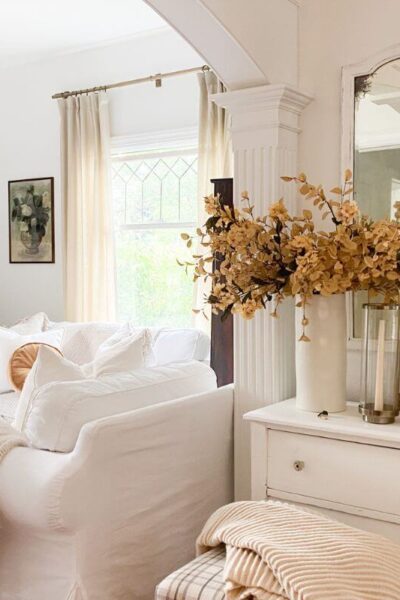 Neutral fall entryway styled with warm autumn branches and antique accents