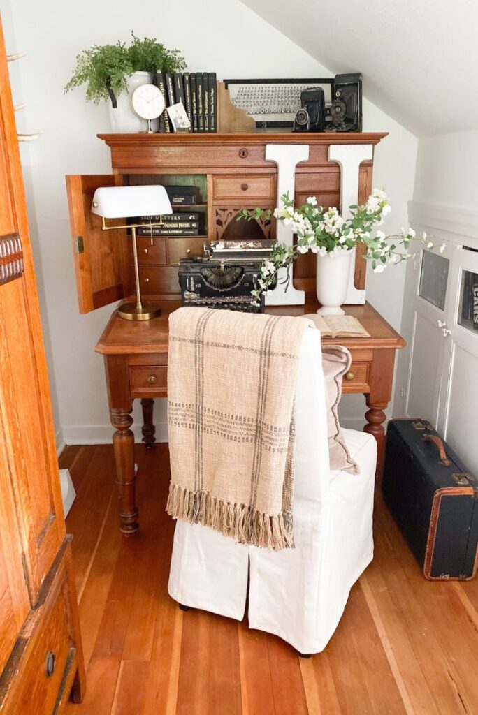 Antique desk with a vintage typewriter, greenery and old books.