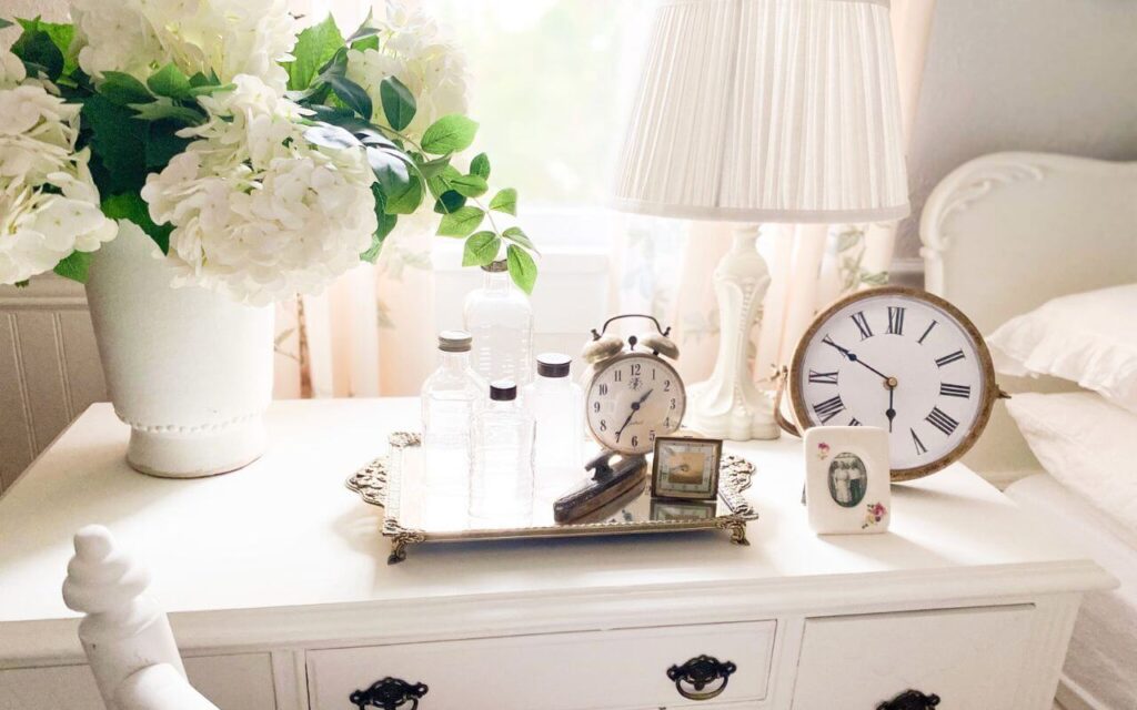 Close up of antique vanity with vintage bottles, clocks and white faux hydrangeas.
