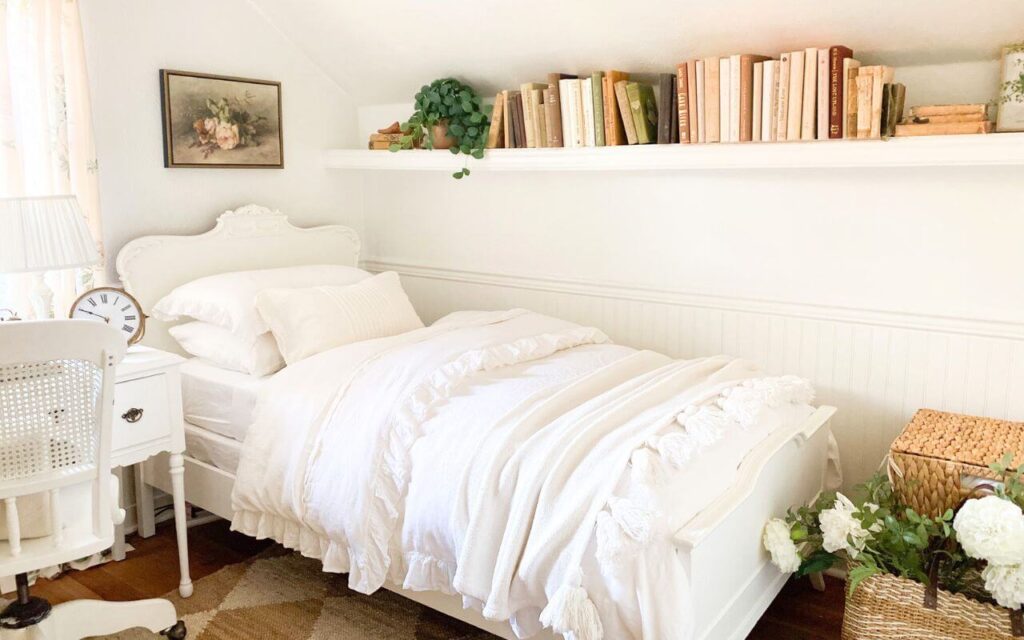 Side view of bed with layered white linens and pink floral artwork