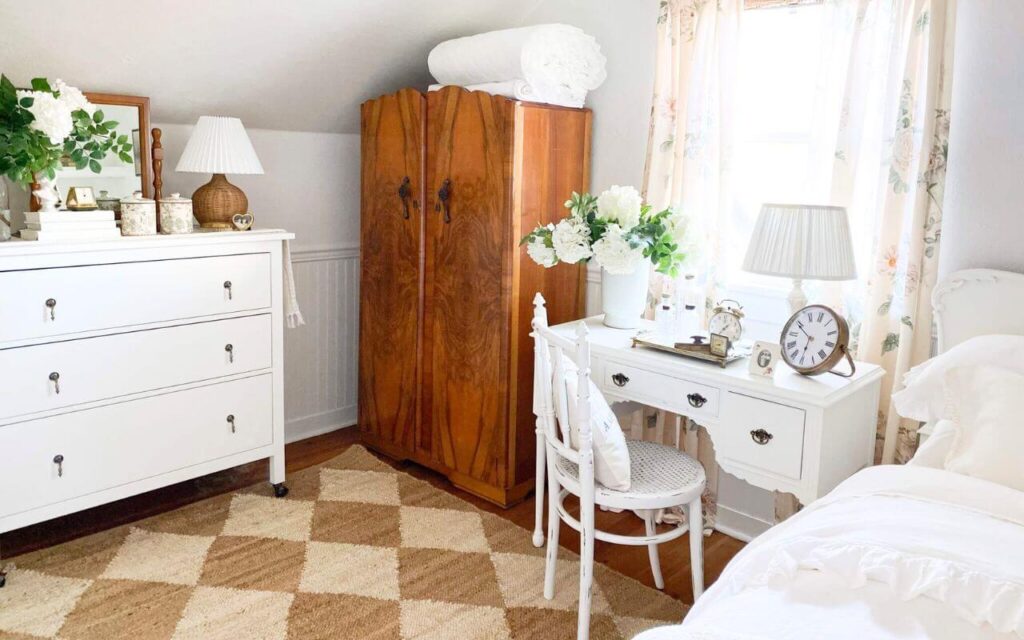 Small guest bedroom with jute diamond rug and florals near window light.