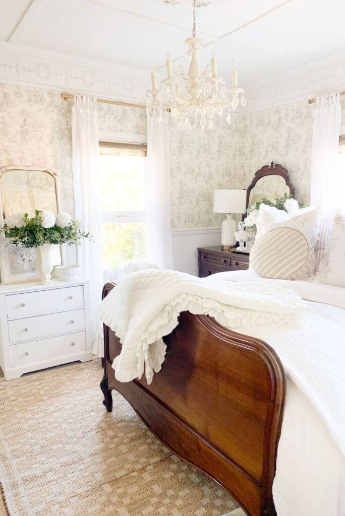 Cottage bedroom with chandelier, ruffled white bedding and patterned jute rug for simple ways to style jute rugs